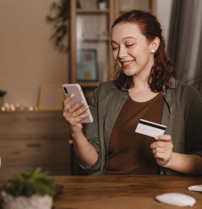 donna-sorridente-utilizzando-il-suo-smartphone-casa-con-carta-di-credito